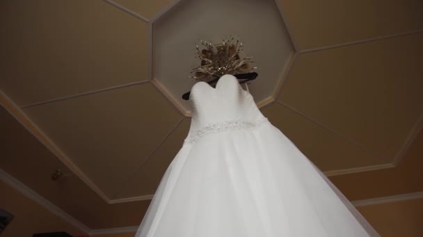 Vestido de novia blanco colgado en una lámpara de araña en una habitación . — Vídeo de stock