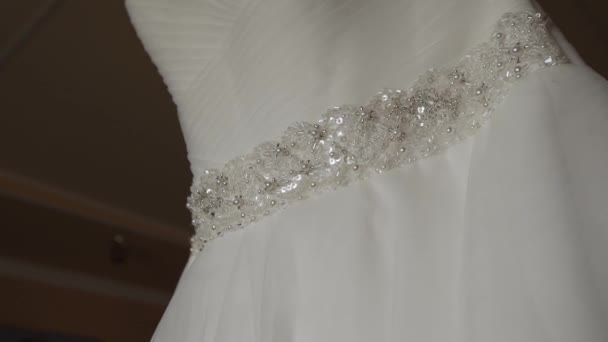 Bílé svatební šaty visí na lustru v pokoji. — Stock video