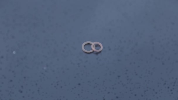 Belos anéis de casamento dourados na superfície molhada com gotas de água . — Vídeo de Stock