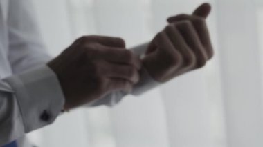 Erkek işadamı kol düğmelerini pencerenin kenarına bağlar.