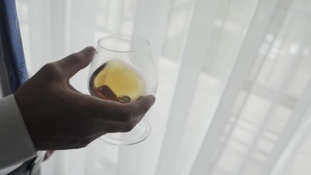 Male businessman with a glass of whiskey by the window. — Stock Video