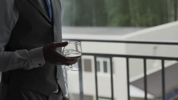 Hombre de negocios con un vaso de whisky junto a la ventana . — Vídeo de stock