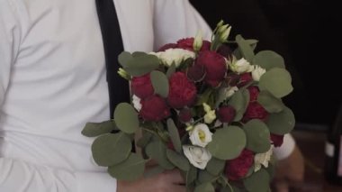 Elinde düğün buketi tutan genç ve mutlu bir adam..