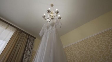 Beyaz gelinlik bir odada bir avizeye asılı..