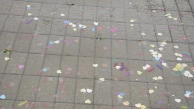 Yağmurda beton kiremit üzerinde çok renkli konfeti kalpleri..