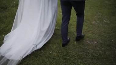 Mutlu gelin ve damat yeşil çimlerde yürüyor.