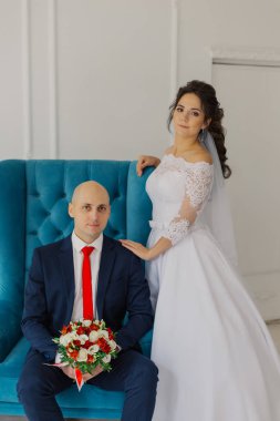 Yakışıklı bir damat sandalyeye oturur. Gelin ayağa kalkar ve ona sarılır..