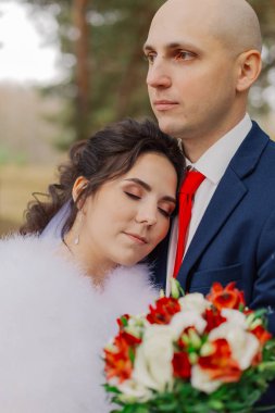 Mutlu gelin ve damat sonbahar ormanında el ele tutuşuyorlar..