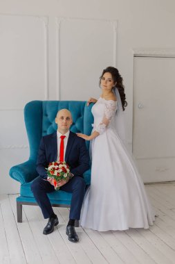 Yakışıklı bir damat sandalyeye oturur. Gelin ayağa kalkar ve ona sarılır..