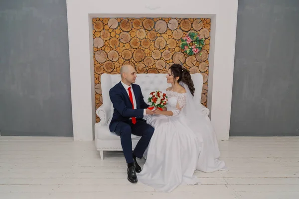Schöne und glückliche Braut und Bräutigam sitzen auf der Couch. — Stockfoto