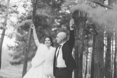 Mutlu gelin ve damat renkli dumanı ellerinde tutuyorlar..