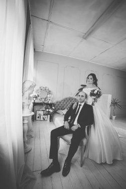 Yakışıklı bir damat sandalyeye oturur. Gelin ayağa kalkar ve ona sarılır..