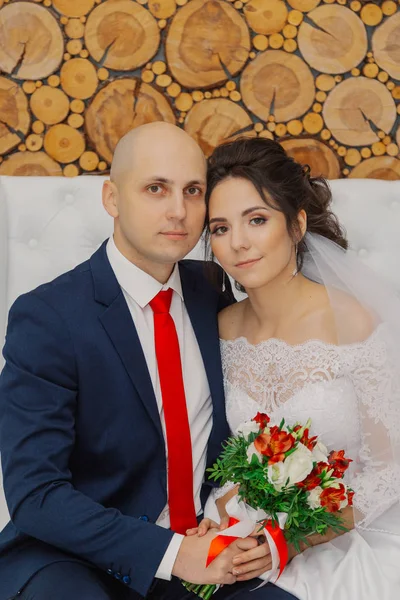 Beautiful and happy bride and groom are sitting on the couch. — Stock Photo, Image