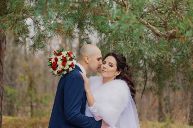 Mutlu gelin ve damat çam ağacının yanında durun ve sarılın..