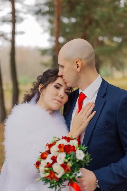 Mutlu gelin ve damat sonbahar ormanında el ele tutuşuyorlar..