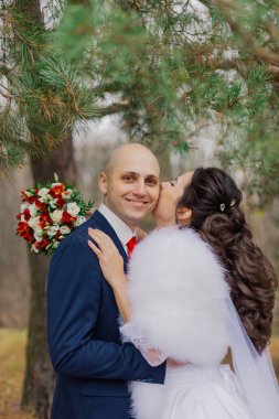 Mutlu gelin ve damat çam ağacının yanında durun ve sarılın..