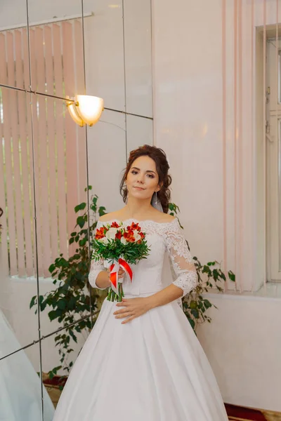 Hermosa novia feliz en una habitación con un ramo de bodas . —  Fotos de Stock