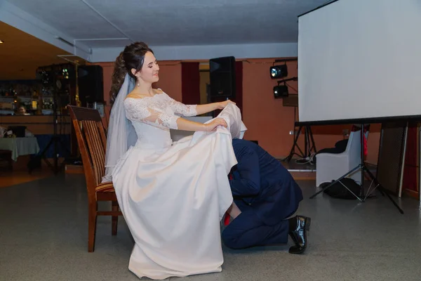 Happy groom takes off the garter from the bride s legs. — 图库照片