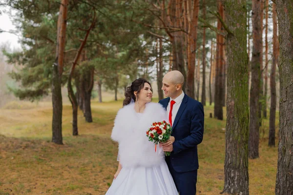 Noiva feliz e noivo estão de pé na floresta de outono de mãos dadas . — Fotografia de Stock