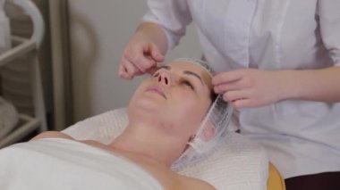 Professional beautician puts a cap on a patient.