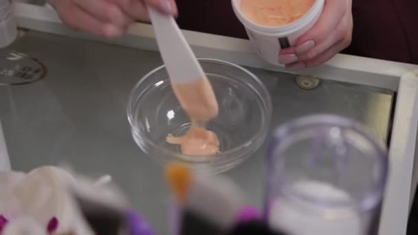 Professional cosmetologist woman stirs a mask in a special container. — Stock Video