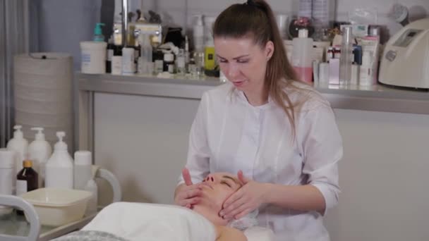 Професійна косметологка робить масаж обличчя пацієнту . — стокове відео