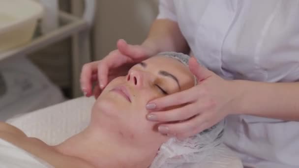 Mulher esteticista profissional fazendo massagem facial para paciente . — Vídeo de Stock