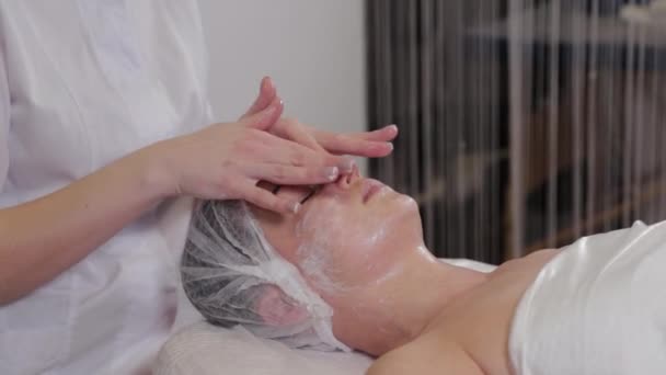 Profesyonel bir güzellik uzmanı hastaların yüzlerini sıvı sabunla yıkar ve aynı zamanda masaj yapar.. — Stok video