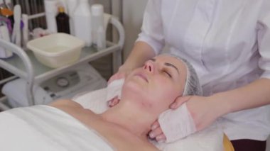 Professional beautician washes face to patient before procedure.