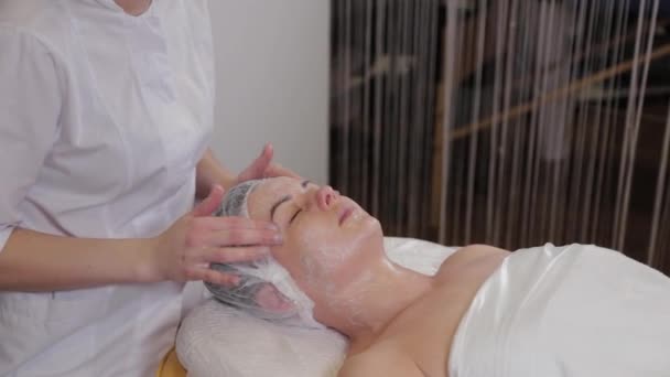 Um esteticista profissional lava o rosto dos pacientes com sabão líquido e massagens simultâneas . — Vídeo de Stock