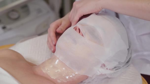 Professionelle Kosmetikerin bedeckt die Maske mit Gesichtsbinden. — Stockvideo