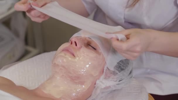 Professionelle Kosmetikerin bedeckt die Maske mit Gesichtsbinden. — Stockvideo