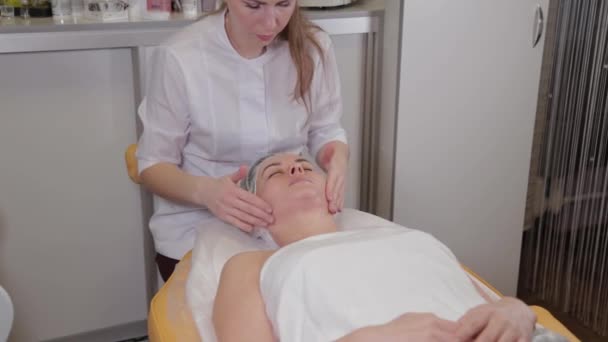 Professionelle Kosmetikerin macht Gesichtsmassage für Kunden des Schönheitssalons. — Stockvideo