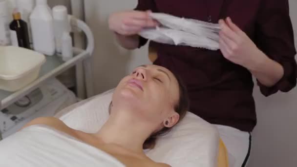 Profesionální kosmetička nasazuje čepici na pacienta. — Stock video