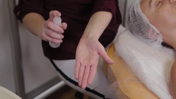 Een verpleegkundige in rubberen handschoenen spray een ontsmettingsmiddel op haar handen, close-up. Een verpleegkundige spuiten op hand desinfecterende oplossing. — Stockvideo