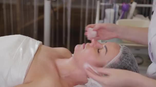 Profesionální kosmetička si před zákrokem umyje obličej pacientovi. — Stock video