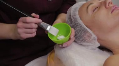 Professional cosmetologist woman stirs a mask in a special container.