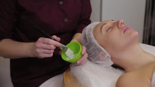 Professional cosmetologist woman stirs a mask in a special container. — Stockvideo