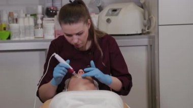 Professional beautician woman performs micronidling facial skin.