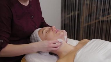 Professional beautician washes face to patient before procedure.