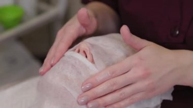 Profesyonel güzellik uzmanı kadın maskeyi yüz bandajlarıyla kapatıyor..