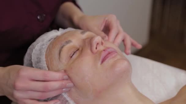 Cosmetóloga profesional haciendo masaje facial al cliente de salón de belleza . — Vídeos de Stock