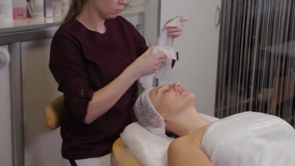 Mujer cosmetóloga profesional quita vendas de la cara de un cliente . — Vídeo de stock