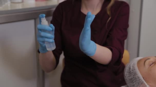 Une infirmière en gants de caoutchouc vaporise un désinfectant sur ses mains, gros plan. Une infirmière éjacule sur une solution désinfectante pour les mains . — Video