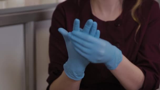 Professionelle Kosmetikerin zieht Gummihandschuhe über ihre Hände. — Stockvideo