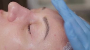 Profesyonel kozmetolog kadın hastalara serum uyguluyor..