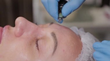 Profesyonel kozmetolog kadın hastalara serum uyguluyor..