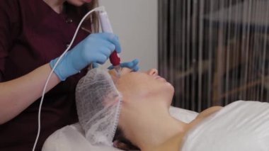 Professional beautician woman performs micronidling facial skin.