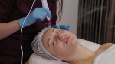 Professional beautician woman performs micronidling facial skin.