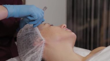 Professional beautician woman performs micronidling facial skin.